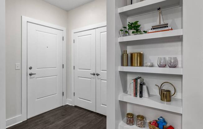 A white shelf with a plant on top and a few other items on it.