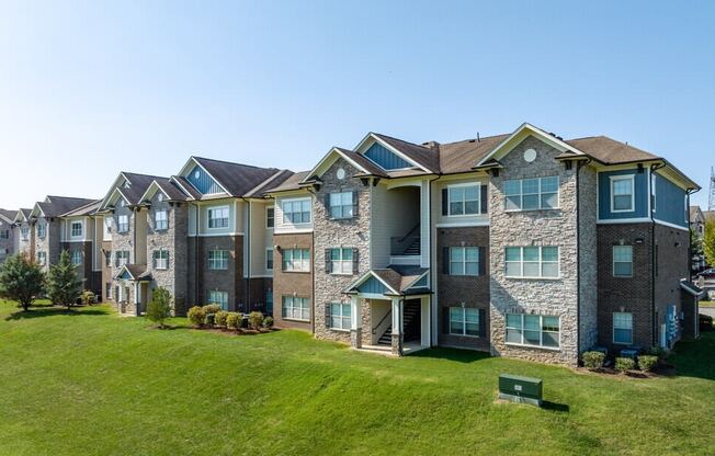 an exterior view of an apartment building with a green lawn