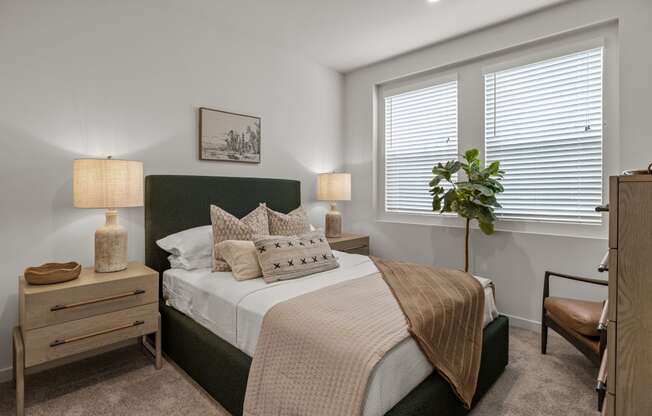 an empty bedroom with a bed and two windowsat Westbury Apartments, Rancho Cucamonga, CA, 91739