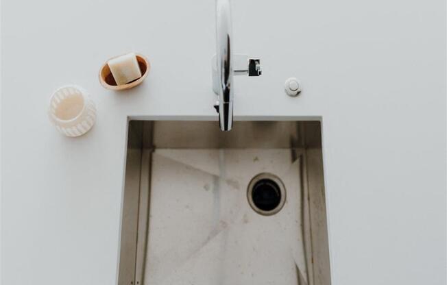 a sink with a faucet and soap on the side of it