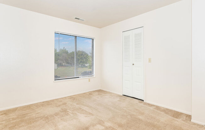 a bedroom with a large window and white walls