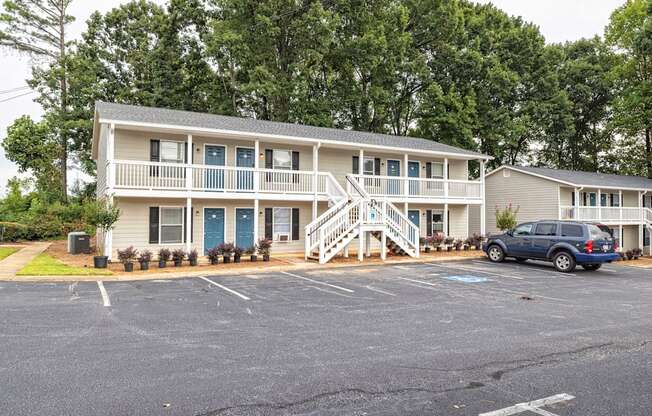 A two-story building with a blue car parked in front.