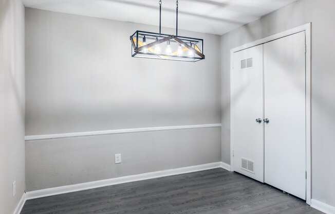 an empty room with white walls and a door and a chandelier