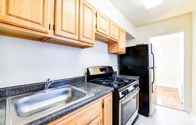 kitchen with wood cabinetry, tile flooring and window at the richman apartments in washington dc