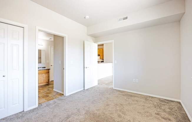 A spacious room with white walls and carpeted floor.