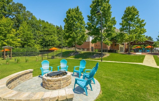 a patio with blue chairs and a fire pit