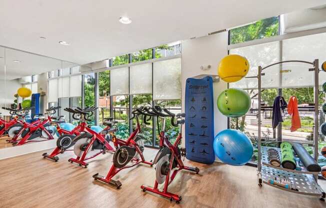 the gym has plenty of exercise equipment and floor to ceiling windows at Link Apartments Innovation Quarter, North Carolina