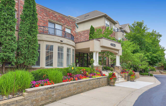 the front of a house with flowers on the sidewalk