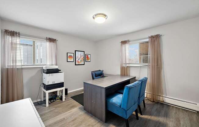A room with a desk, chair, and a pile of books.