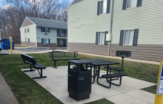 a picnic table and a trash can in front of a building