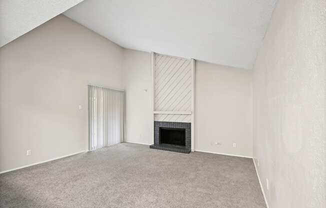 an empty living room with a fireplace and a sliding glass door