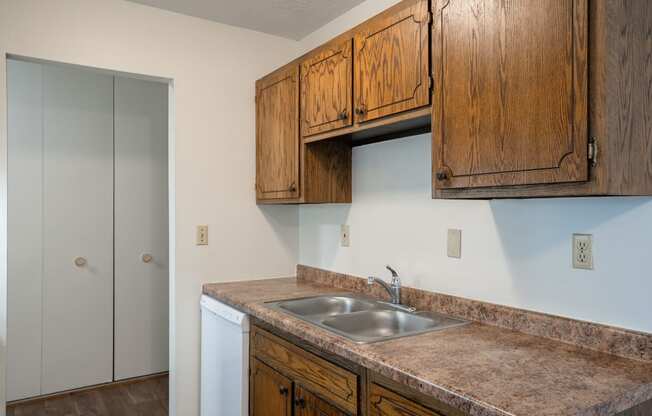 a kitchen with a sink and cabinets and a door to a closet.  Eagan, MN Glen Pond Apartments