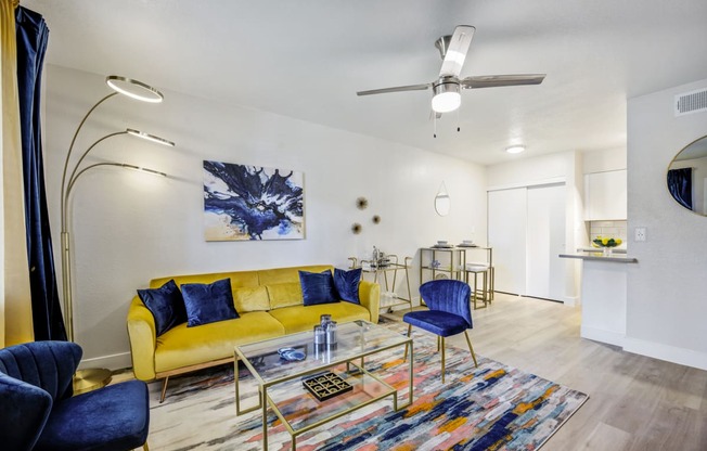 a living room with a yellow couch and blue chairs