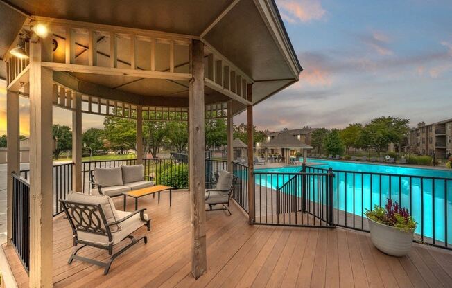 a poolside deck with chairs and a gazebo overlooking a swimming pool