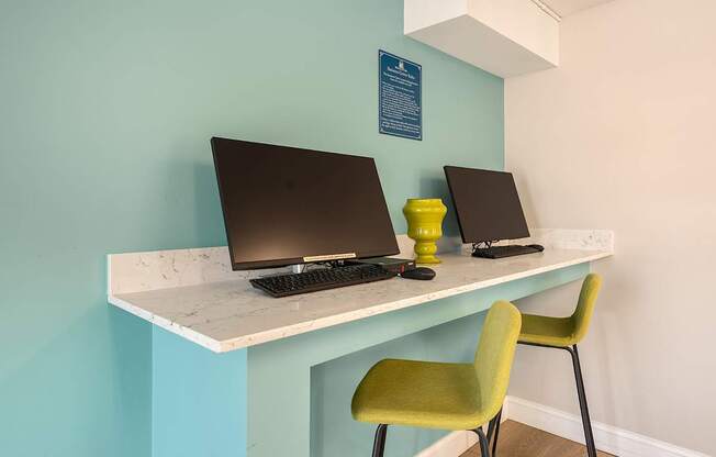 Two laptops are on a desk with a green chair.