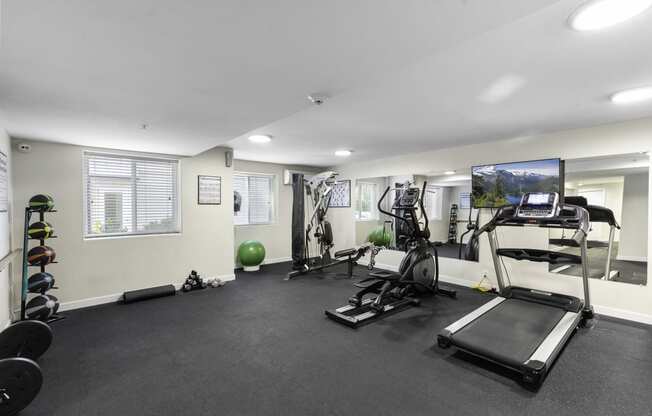 a gym with exercise equipment and a flat screen tv at West Mall Place Apartment Homes, Everett, WA