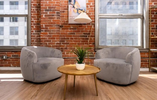 two chairs and a table in a room with a brick wall