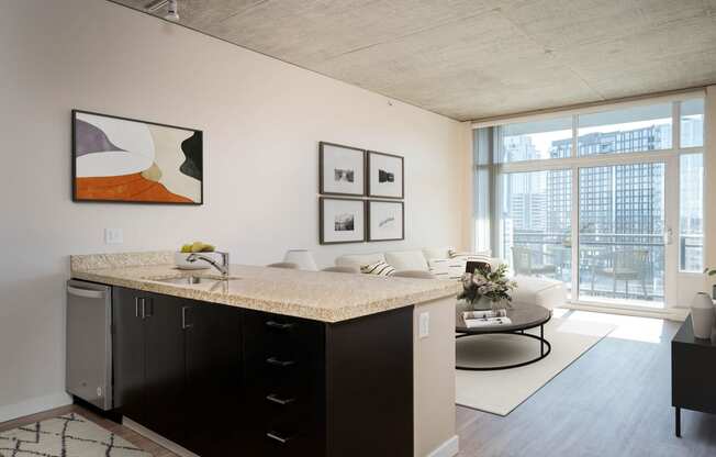 a living room with a large window and a kitchen with a counter top