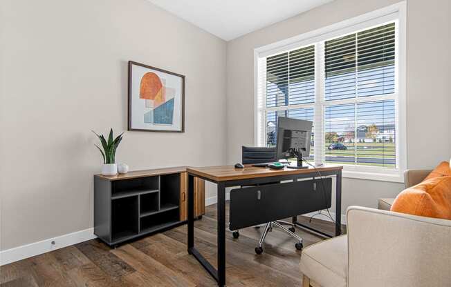 a desk with a computer and a chair in a room with large windows