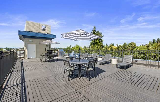 a large outdoor resident deck with chairs and umbrellas at Guinevere Apartment Homes in  Seattle, Washington