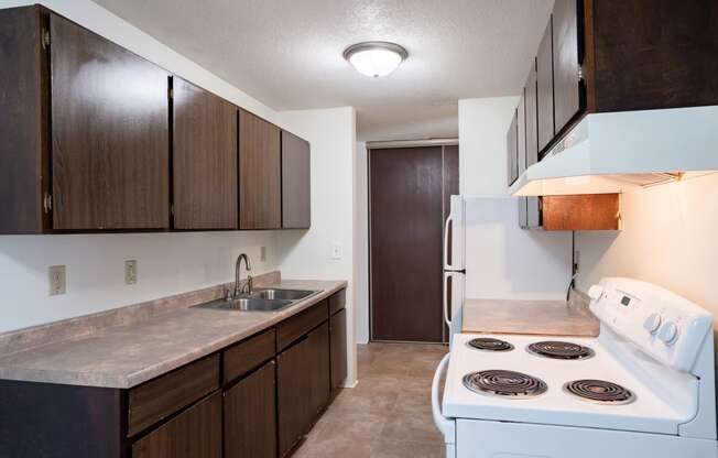 a kitchen with white appliances and wooden cabinets and a white stove. Coon Rapids, MN Robinwood Apartments