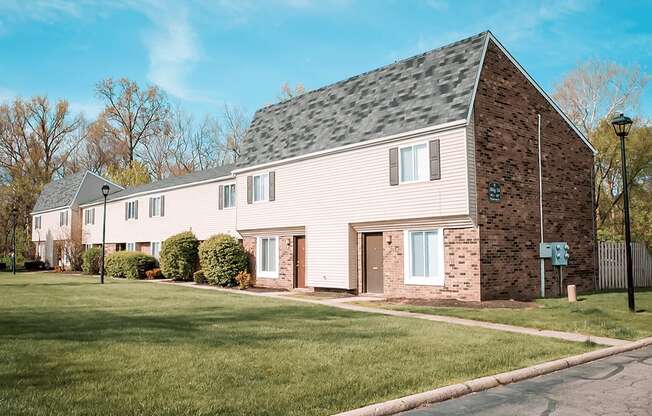 a white and brick house with a yard in front of it