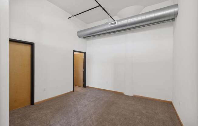 an empty living room with white walls and a door to a hallway