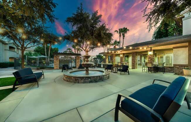 A patio with a fire pit and chairs.