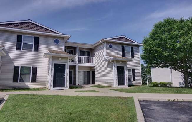 an apartment building with white siding and a sidewalk