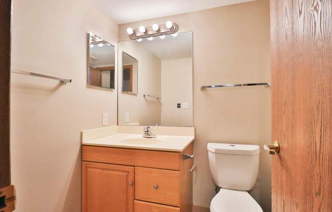 A bathroom with a toilet, sink, and mirror.