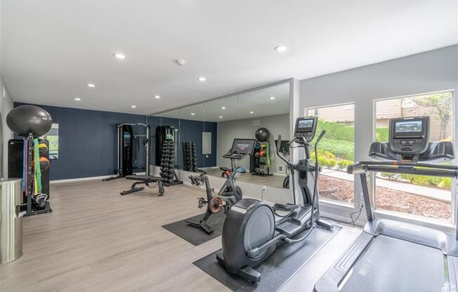 A spacious gym with a variety of equipment including treadmills, elliptical machines, and weight machines.