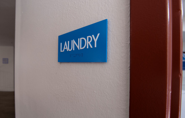A blue sign on a wall that says Laundry.