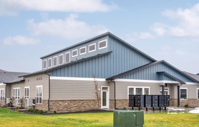 the front of the clubhouse with a blue and gray roof and a green lawn