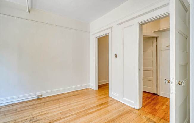 A room with white walls and wooden floors with two doors.