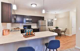 the view of a kitchen and dining room with a large counter top with a bar