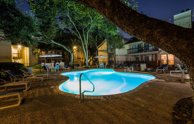 a pool at night with a tree in the foreground