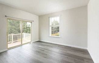 an empty living room with wood floors and a balcony