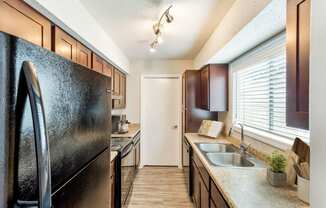 Hunters Pointe Apartments in Charlotte North Carolina photo of a kitchen with brown cabinets and a black refrigerator