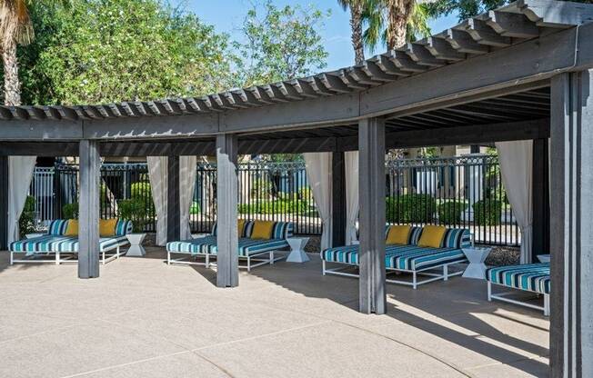 Covered lounge chairs near pool - Lunaire Apartments | Goodyear, Arizona