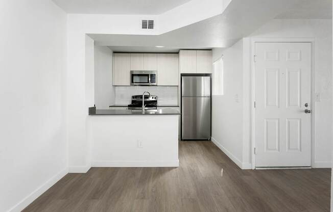 A kitchen with a refrigerator, microwave, and oven.