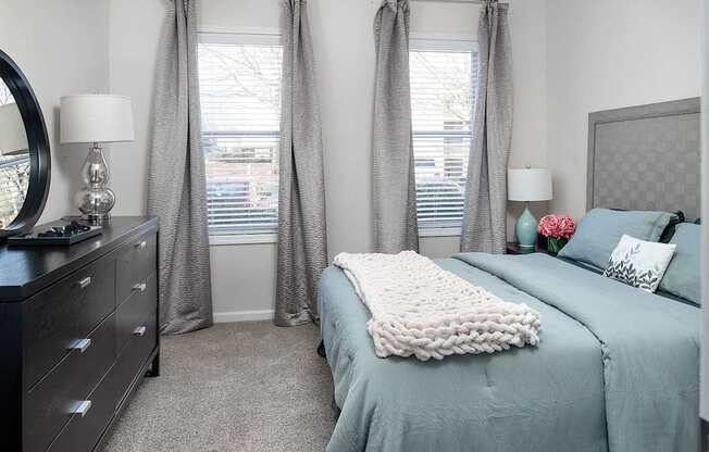 A bedroom with a large bed and a dresser with a mirror.