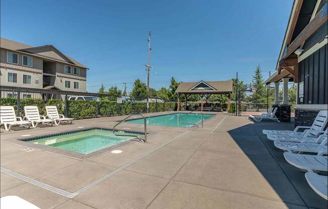 A large outdoor swimming pool with lounge chairs and a gazebo at Forestplace Apartment Homes, Forest Grove, Oregon