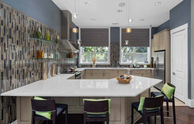 A kitchen with a white countertop and a white island with four chairs around it.
