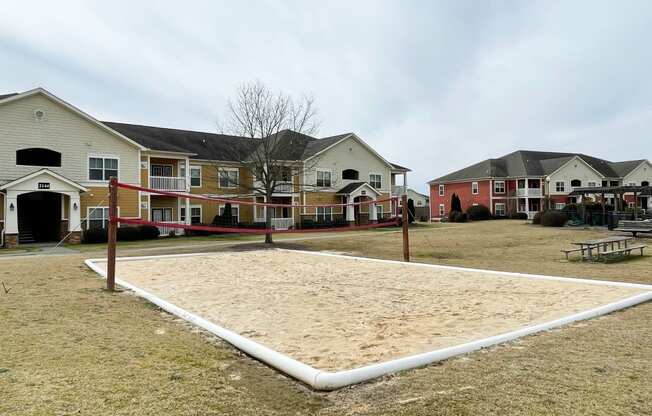 a sand volleyball court in front of a row of houses