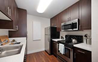 full kitchen with stainless steel appliances and dark wood cabinets