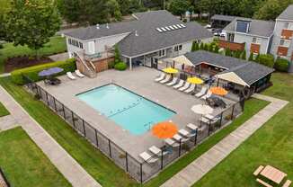 a large yard with a swimming pool and a house with umbrellas