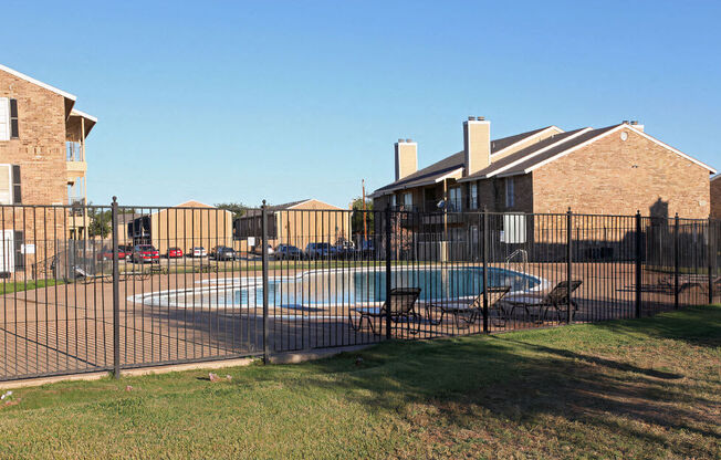 a swimming pool in front of a house behind a fence