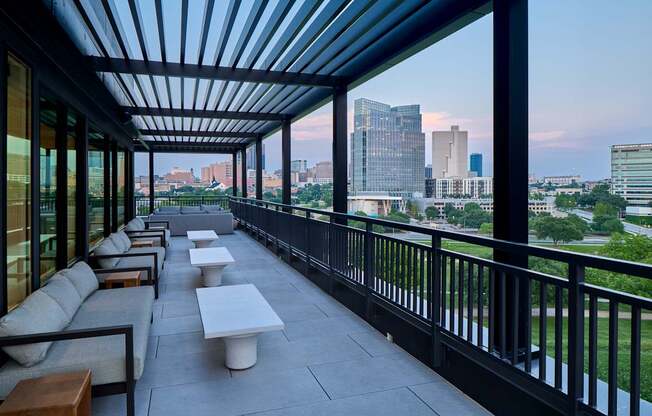 A patio with a black railing and a view of the city.