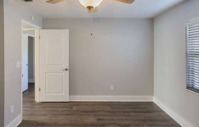 an empty living room with a white door and a ceiling fan