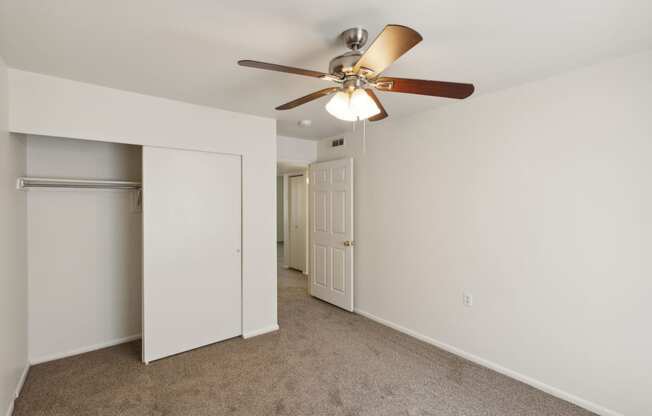 a bedroom with a ceiling fan and a closet